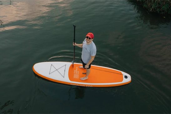 Beginner paddleboarder maintaining balance on a wide, stable SUP on a calm river