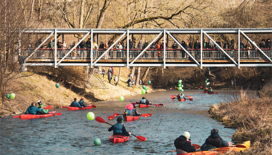Group of kayakers paddling under a bridge on a river
